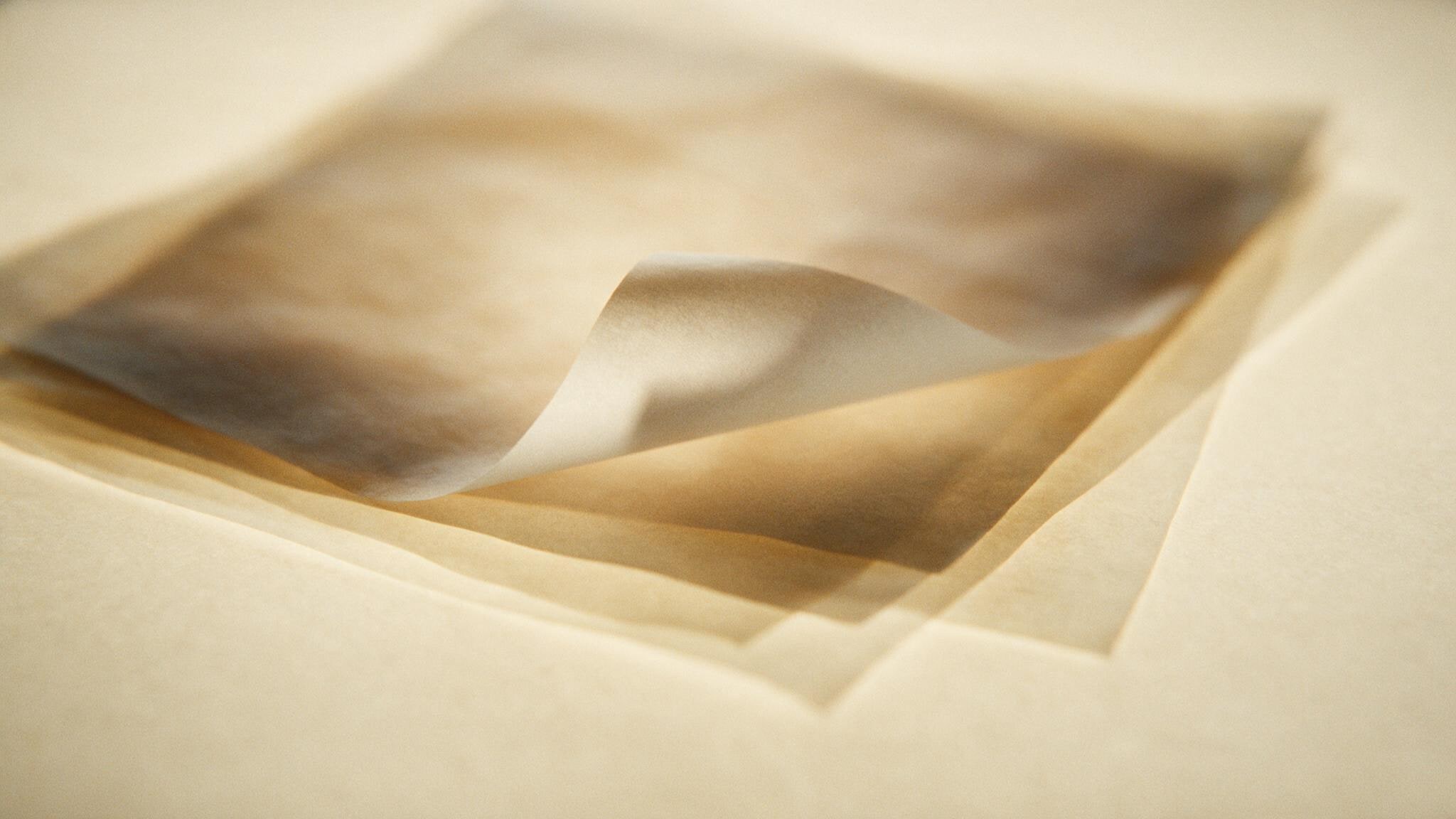Sheets of translucent vellum layered over one another on warm cream, backlit so the overlapping edges read as soft tonal steps.