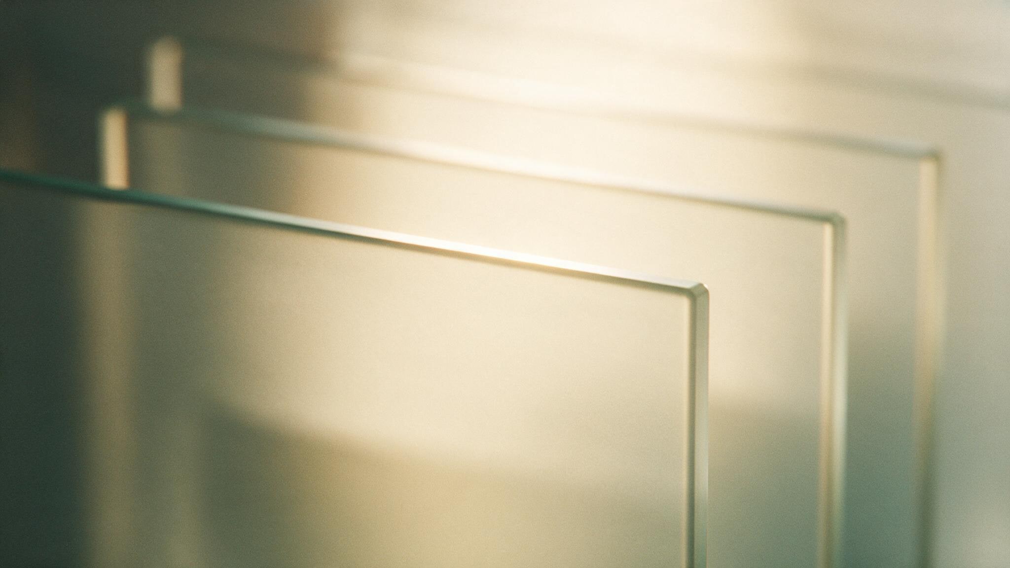Layered panes of frosted glass receding into soft focus, lit from behind in warm cream light.